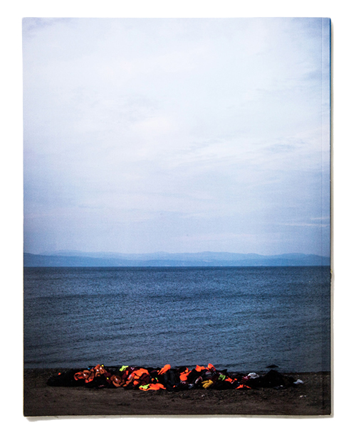 A photograph of life jackets stacked on the beach in a magazine spread